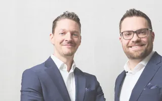 Geschäftsführer Sven Tippelt und Julian Grauer neben dem Slogan: "Bestens informiert: Die Maklerwelt von Adam Riese"