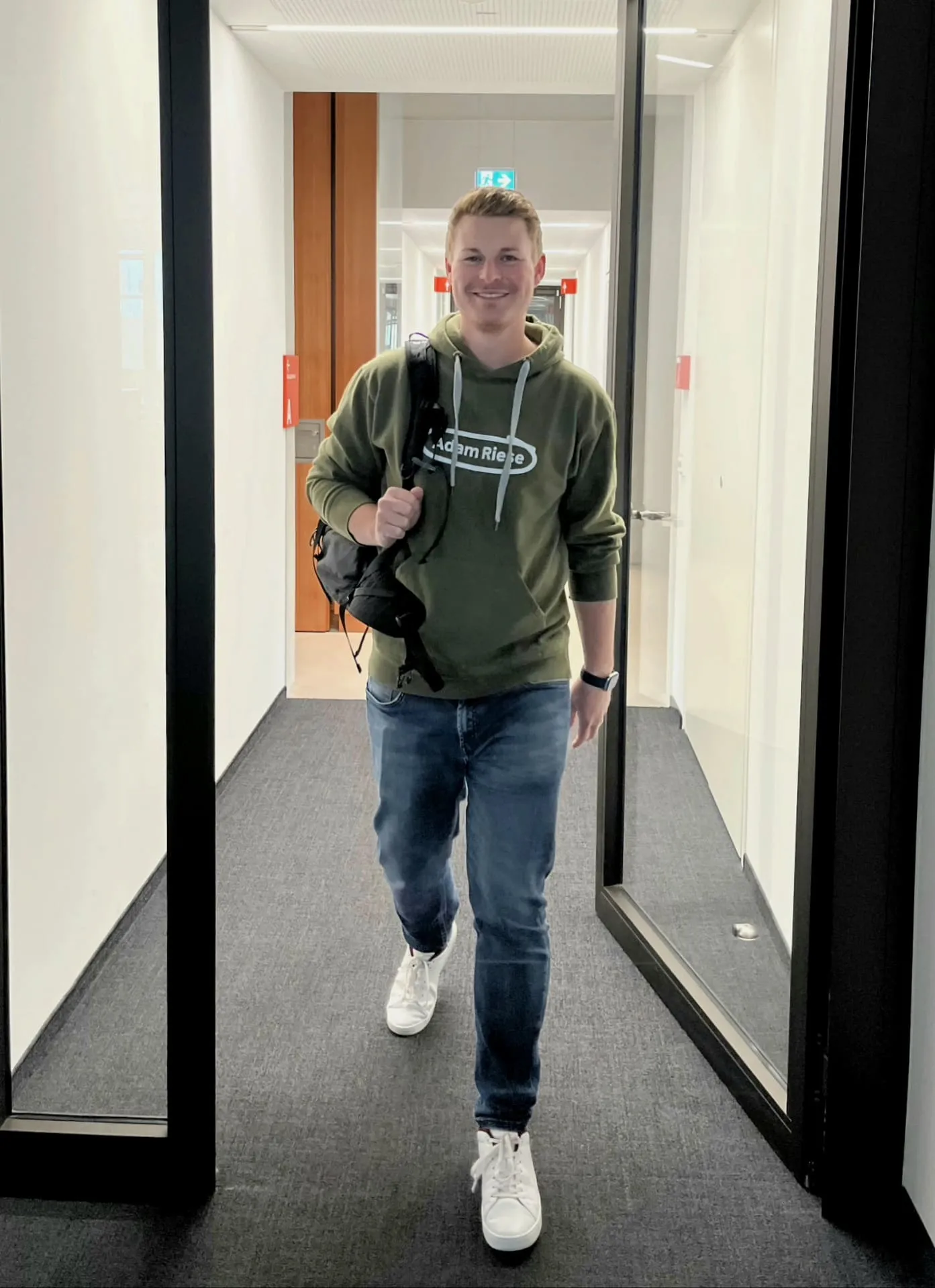 Moritz, wie er im Hoodie und Jeans das Office verlässt.