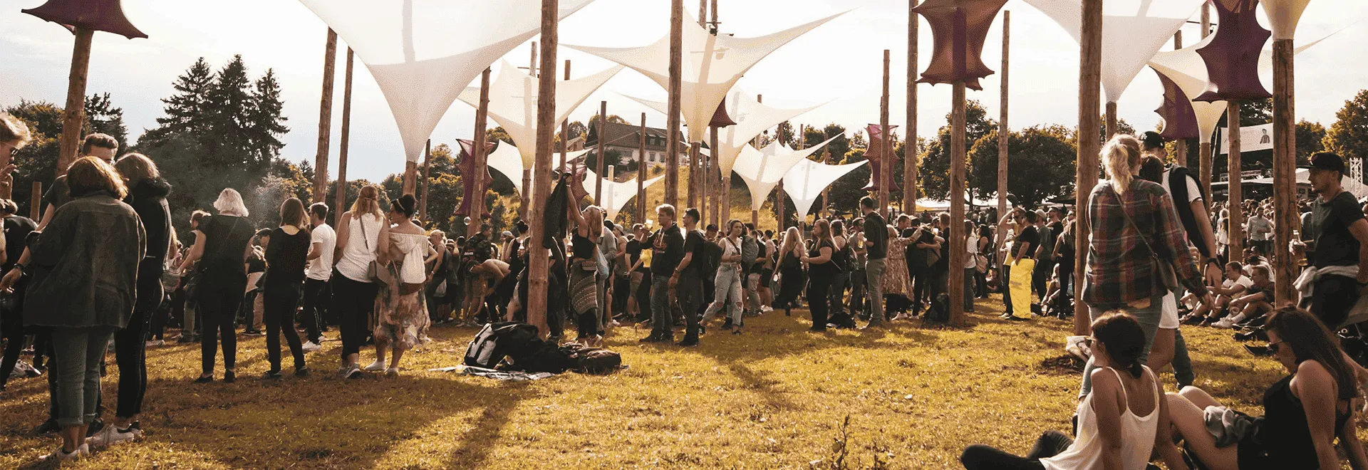 Mit dem Festival-Guide bist Du auch hier auf alles vorbereitet: Eine Festival-Wiese mit Dekorationen und Festivalgängern in der Abendsonne.