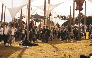 Mit dem Festival-Guide bist Du auch hier auf alles vorbereitet: Eine Festival-Wiese mit Dekorationen und Festivalgängern in der Abendsonne.
