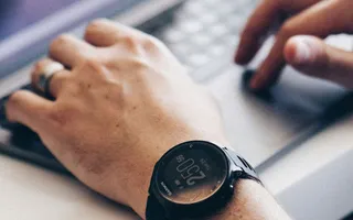 Ob diese Person auch gerade ihre Unfallversicherung kündigen will? Sie sitzt am Laptop und schreibt. Am linken Handgelenk sieht man eine Uhr.