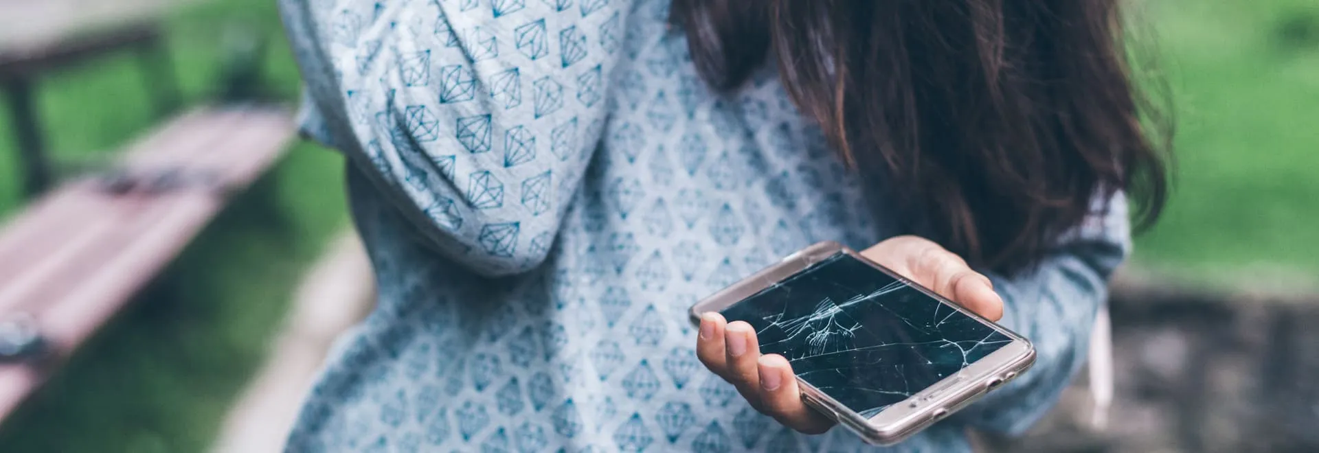 Eine Person hält ein Smartphone mit zersplittertem Display in der Hand.