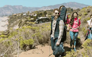 Ob die noch Tipps beim Wandern brauchen ? Fünf Freunde auf einem sonnigen Wanderweg am Meer.