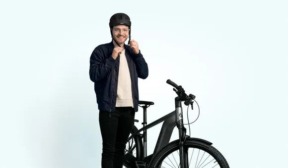Mann am Helm anziehen neben seinem E-Bike