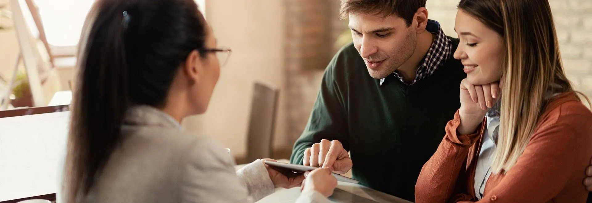 Ein Mann und eine Frau sitzen einer Anwältin gegenüber und lassen sich etwas auf einem Tablet zeigen. Welche Rechtsschutzversicherung-Leistungen sie wohl brauchen?