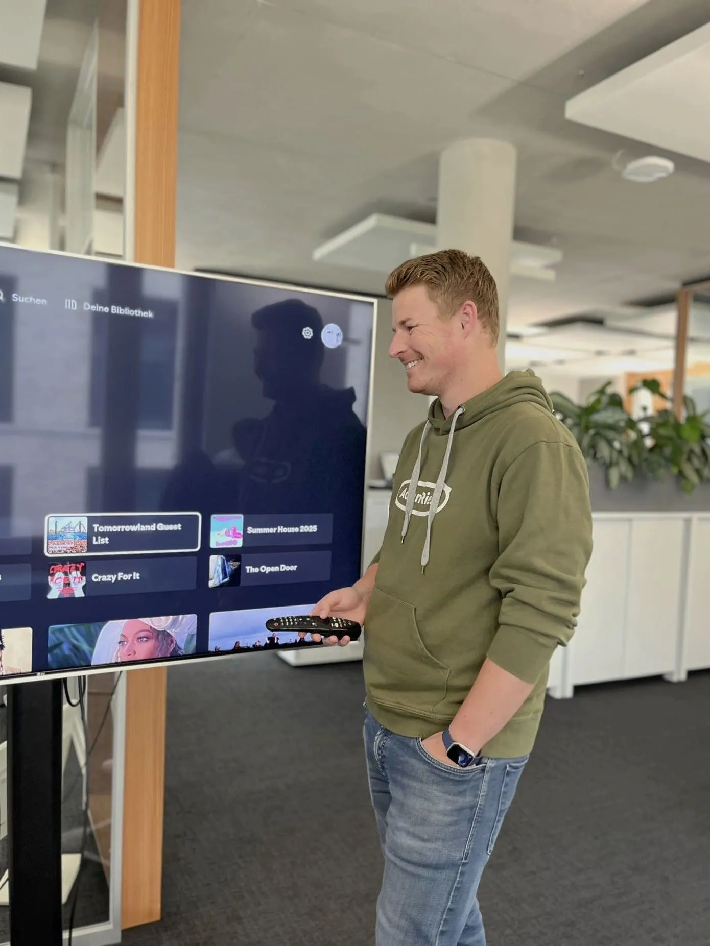 Moritz steht vor einem großen Bildschirm und klickt in seinem Spotify herum.