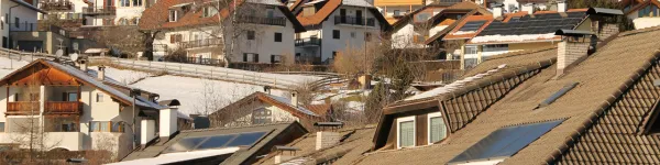 Ein herbstlich-winterlicher Blick über Häuserdächer mit Solaranlagen.