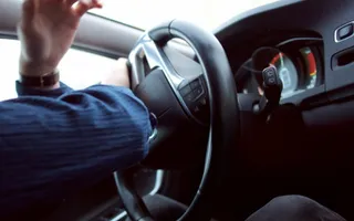 Eine Person sitzt am Lenkrad eines Autos und steuert stark nach links.