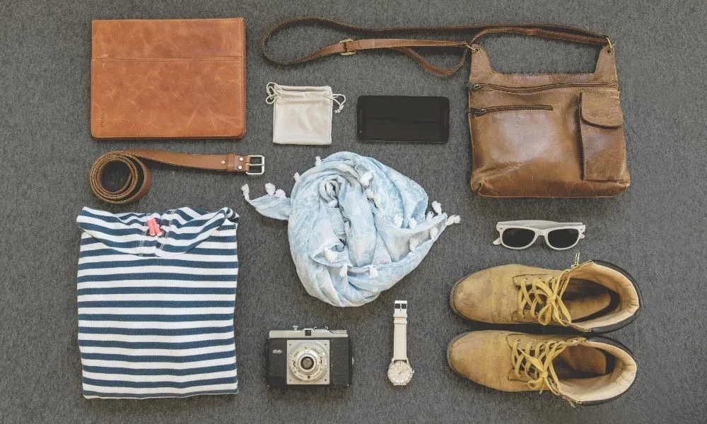 Minimalistische Ausrüstung: T-Shirt, Schal, Schuhe, Sonnenbrille, Smartphone.