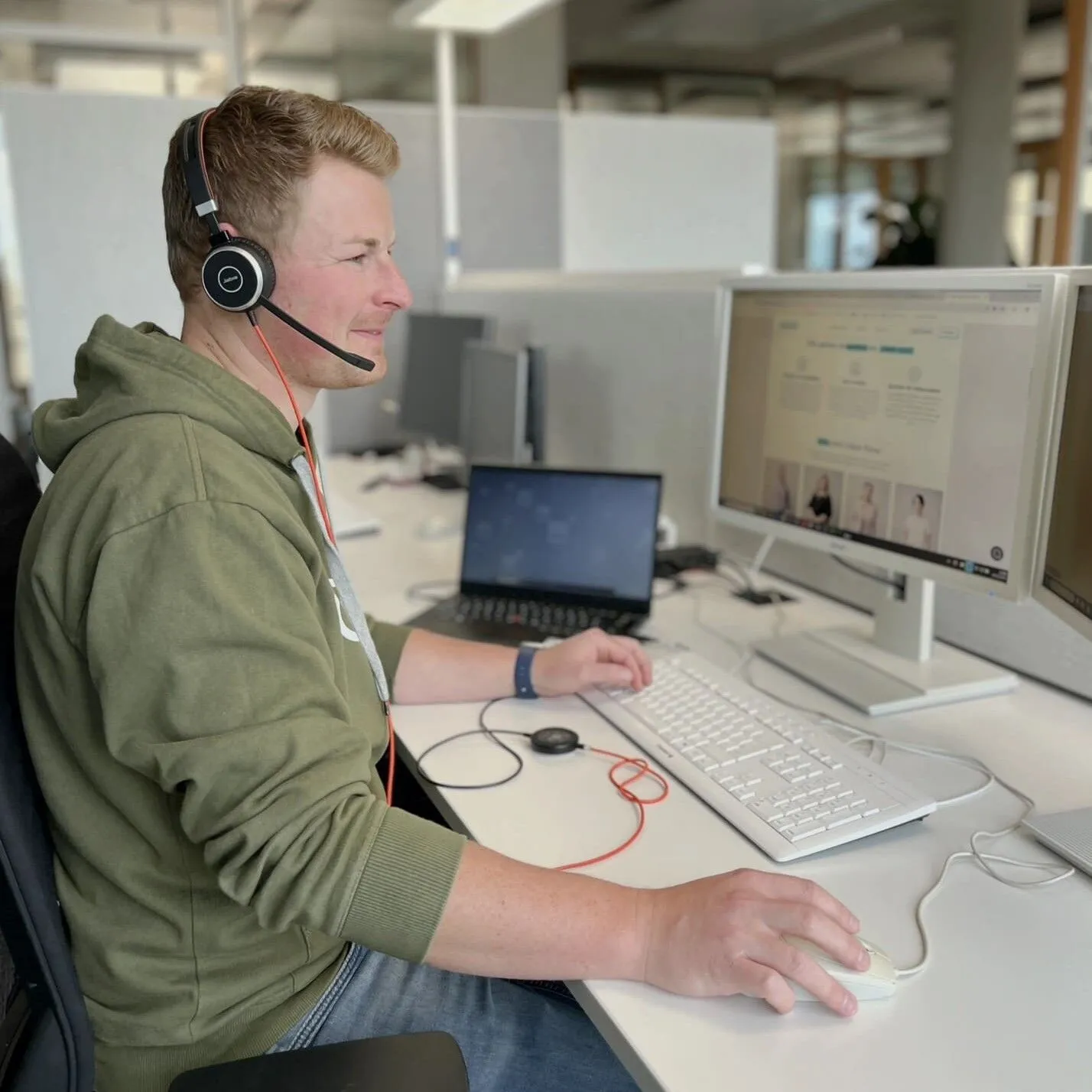 Moritz sitzt an seinem Schreibtisch mit Headset auf und arbeitet fleißig.