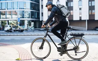 E-Bike-Fahrer in der Stadt mit passender Adam Riese Versicherung