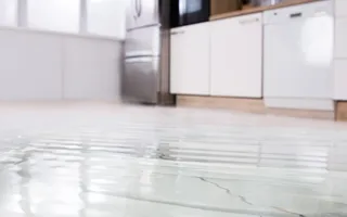 Wasser sammelt sich auf einem weißen Küchenboden.