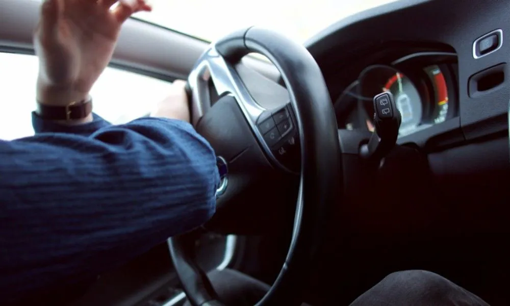 Eine Person sitzt am Lenkrad eines Autos und steuert stark nach links.